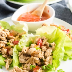 Chicken Lettuce Wraps on a white plate with a bowl of sweet chili sauce.