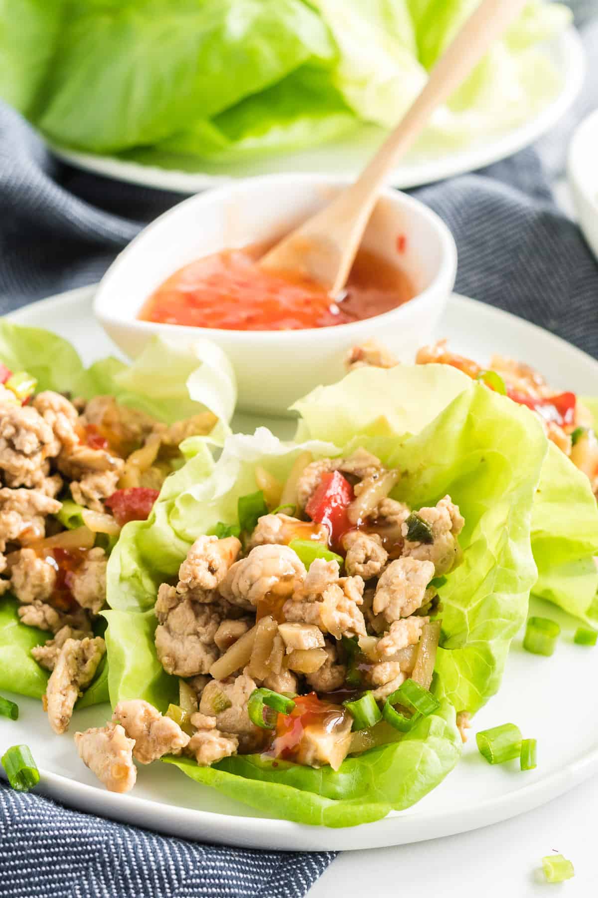 Chicken Lettuce Wraps on a white plate with a bowl of sweet chili sauce.