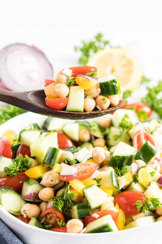A wooden spoon scoops up some of the Chickpea Salad.
