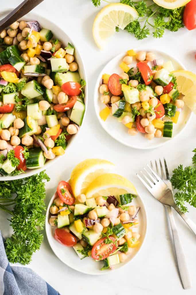 Two small white plates with a serving of Chickpea Salad and lemon slices.
