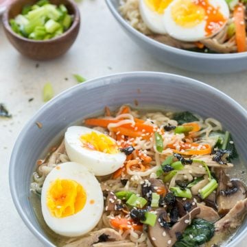 close up image of low sodium instant pot ramen with sliced green onions in a small bowl