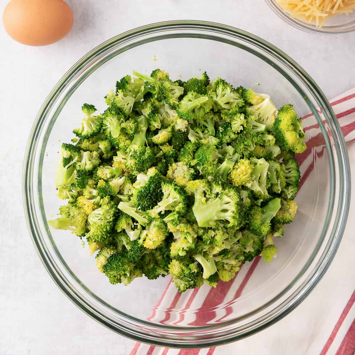 Partially cooked chopped broccoli in a glass bowl.