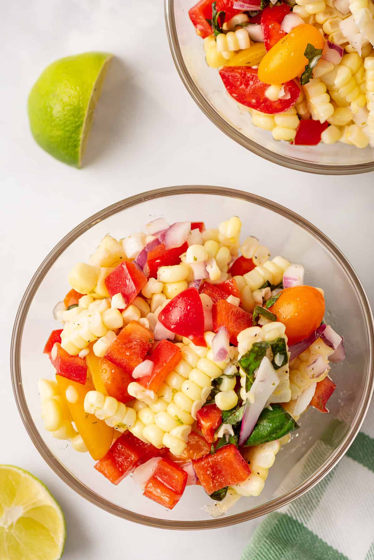 A glass bowl filled with corn and tomato salad