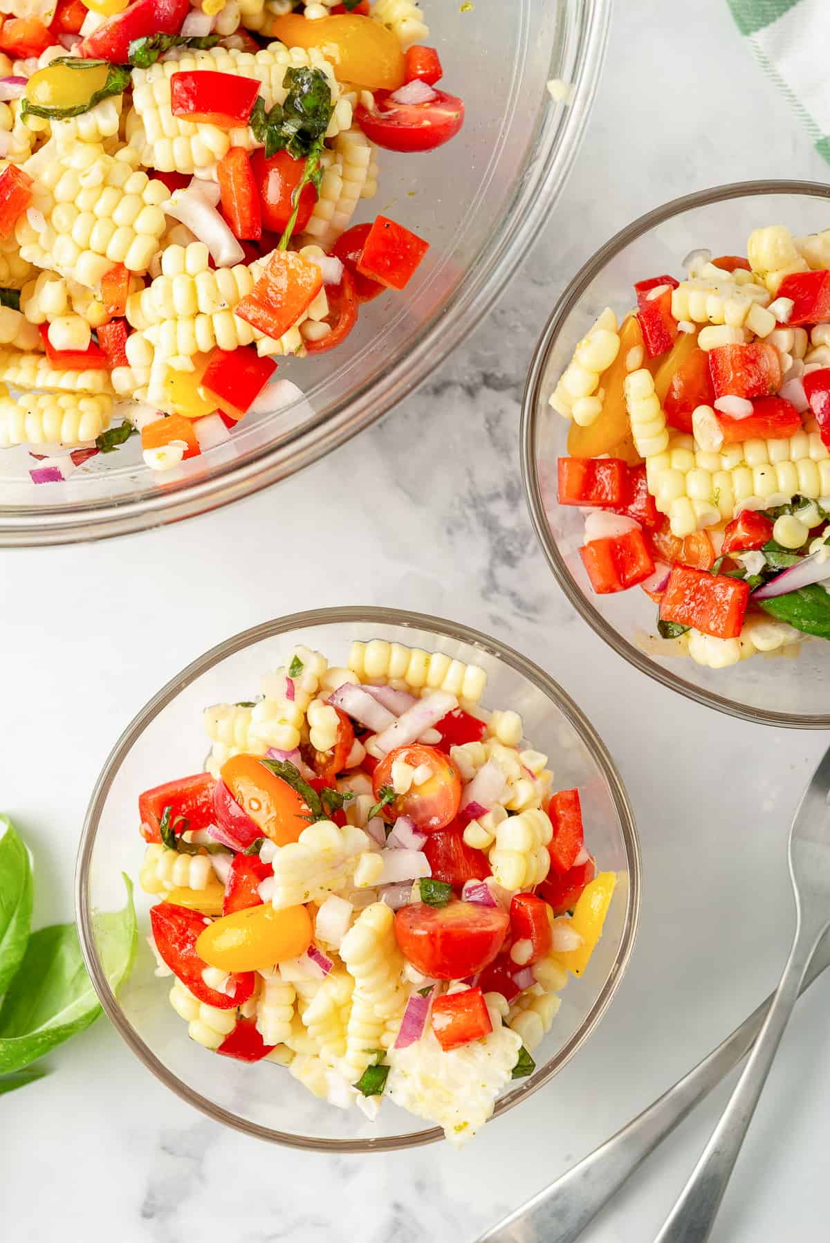 Two small bowls filled with corn salad with a larger bowl in the background.