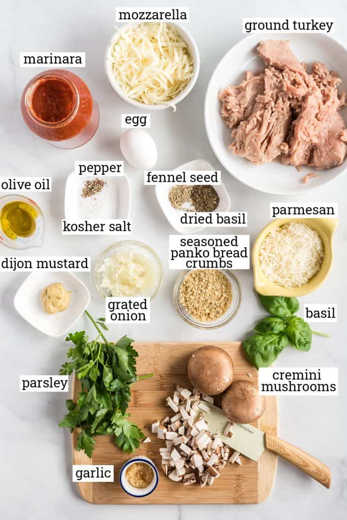 Ground turkey, mushrooms and other ingredients on a white surface.