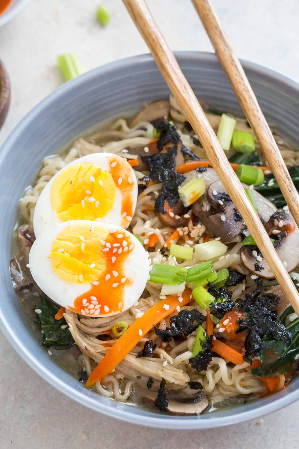 Ramen in a bowl with a soft boiled egg and chopsticks.