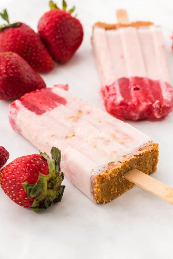 strawberry cheesecake popsicles and fresh strawberries on table