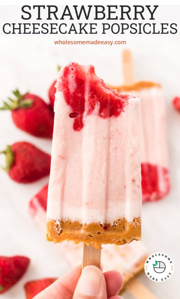A hand holds a Strawberry Cheesecake Popsicle.