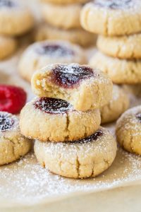 Raspberry Almond Thumbprint cookies stacked with a bite missing from the top cookie.