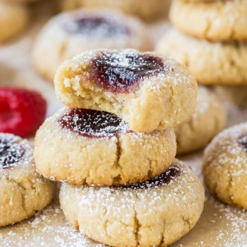 Raspberry Almond Thumbprint cookies stacked with a bite missing from the top cookie.