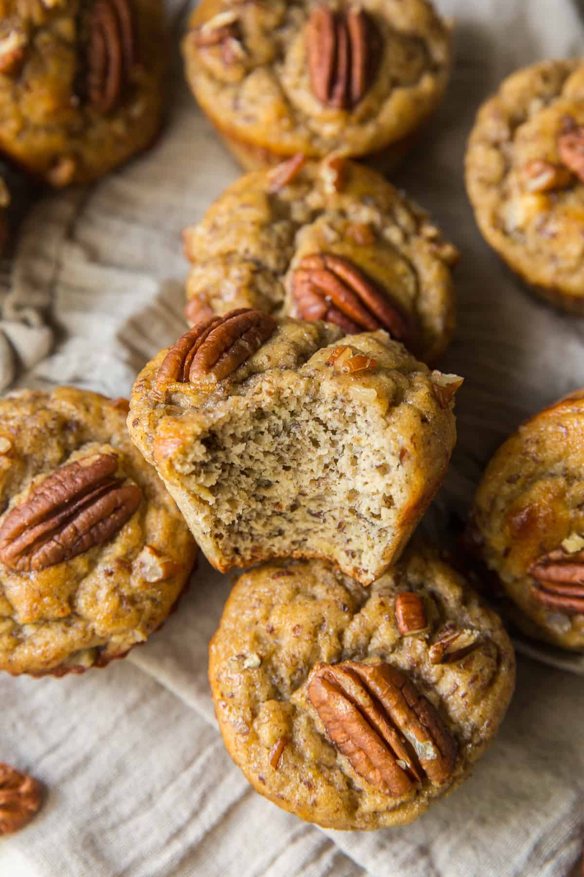 A stack of banana pecan muffins with a bite missing from the one on top.