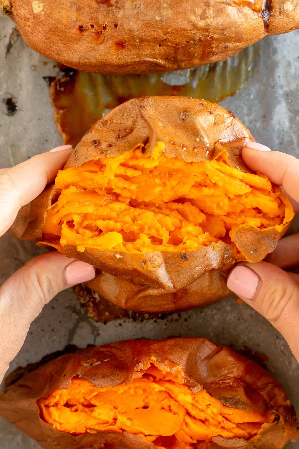 Hands squeeze the ends of a sweet potato to open it up.