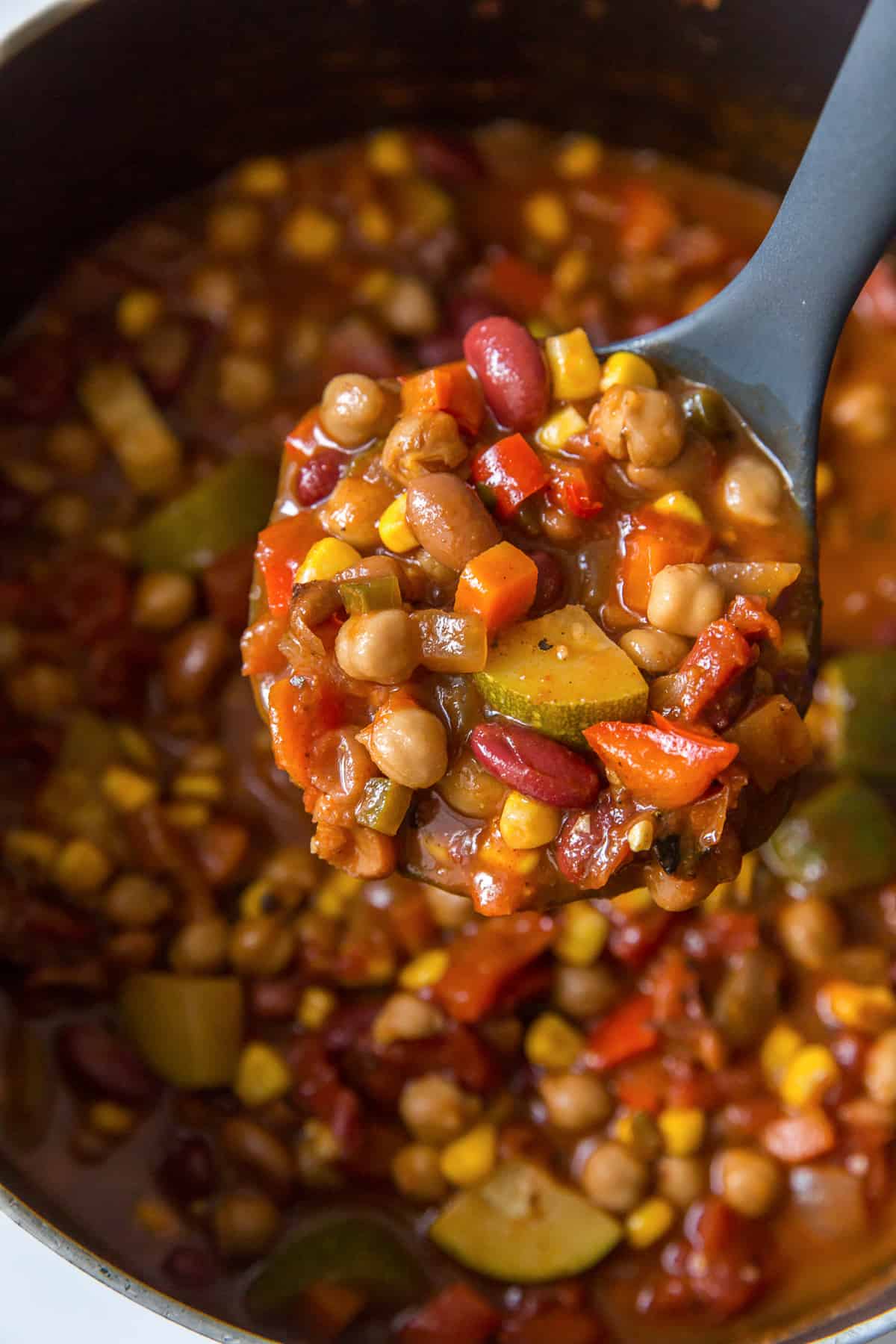 A ladle scoops veggie chili from a pot.