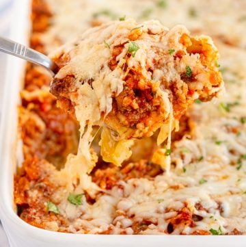 A spoon scoops up cabbage roll casserole from a baking dish.