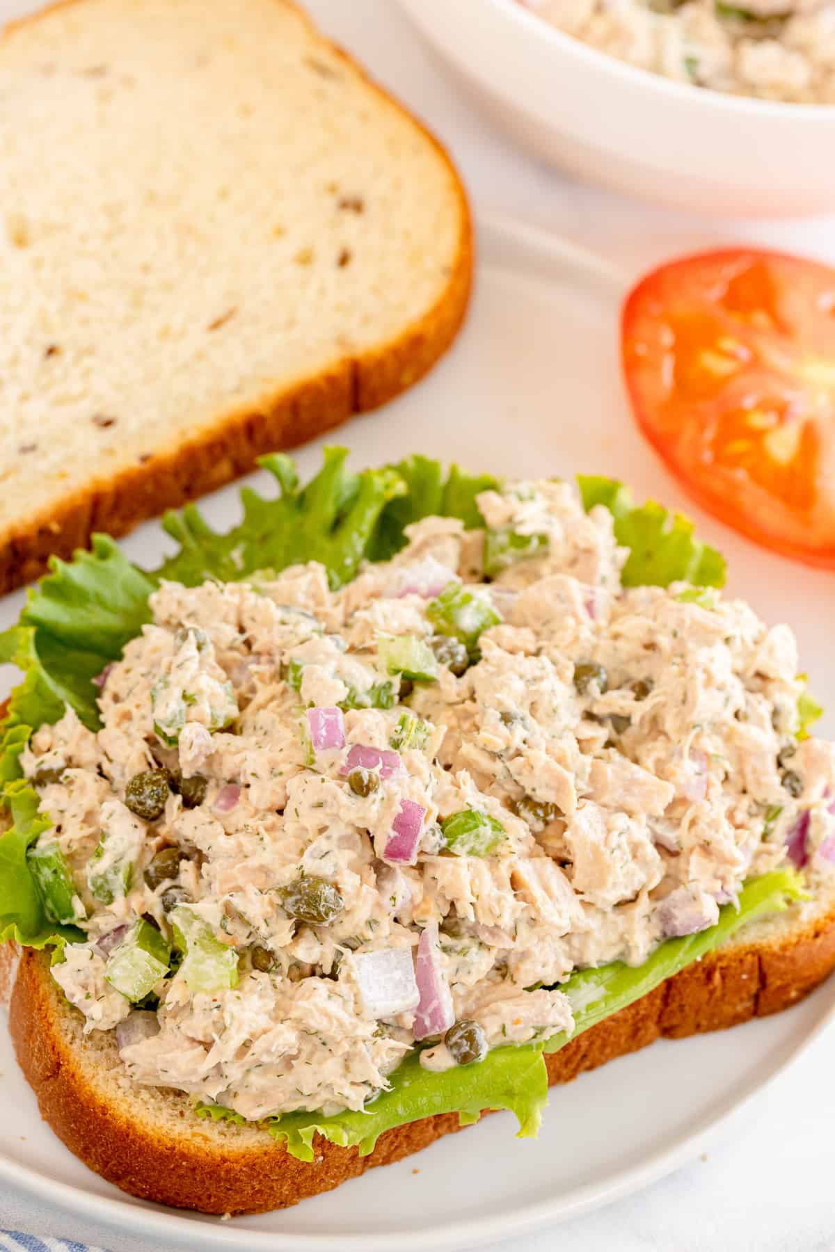 A slice of bread topped with lettuce and tuna salad.