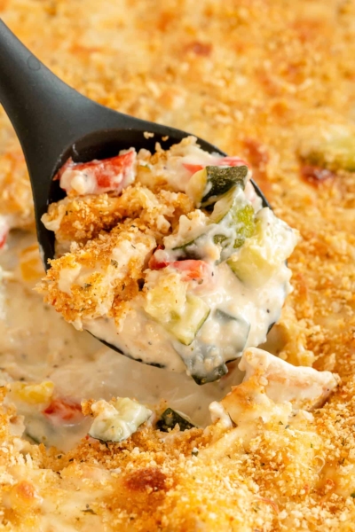 A serving spoon scoops up Chicken and Zucchini Casserole.