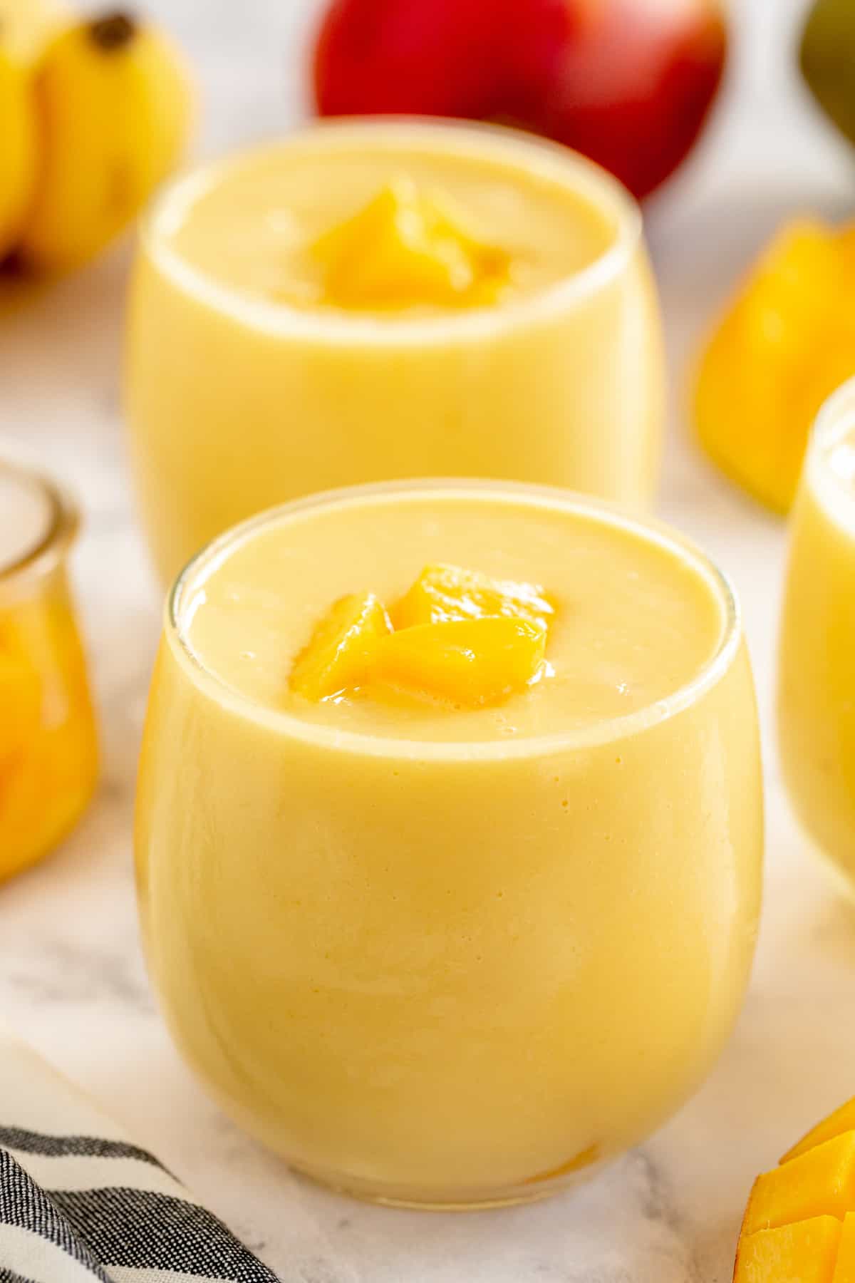 Two mango smoothies in small glasses.