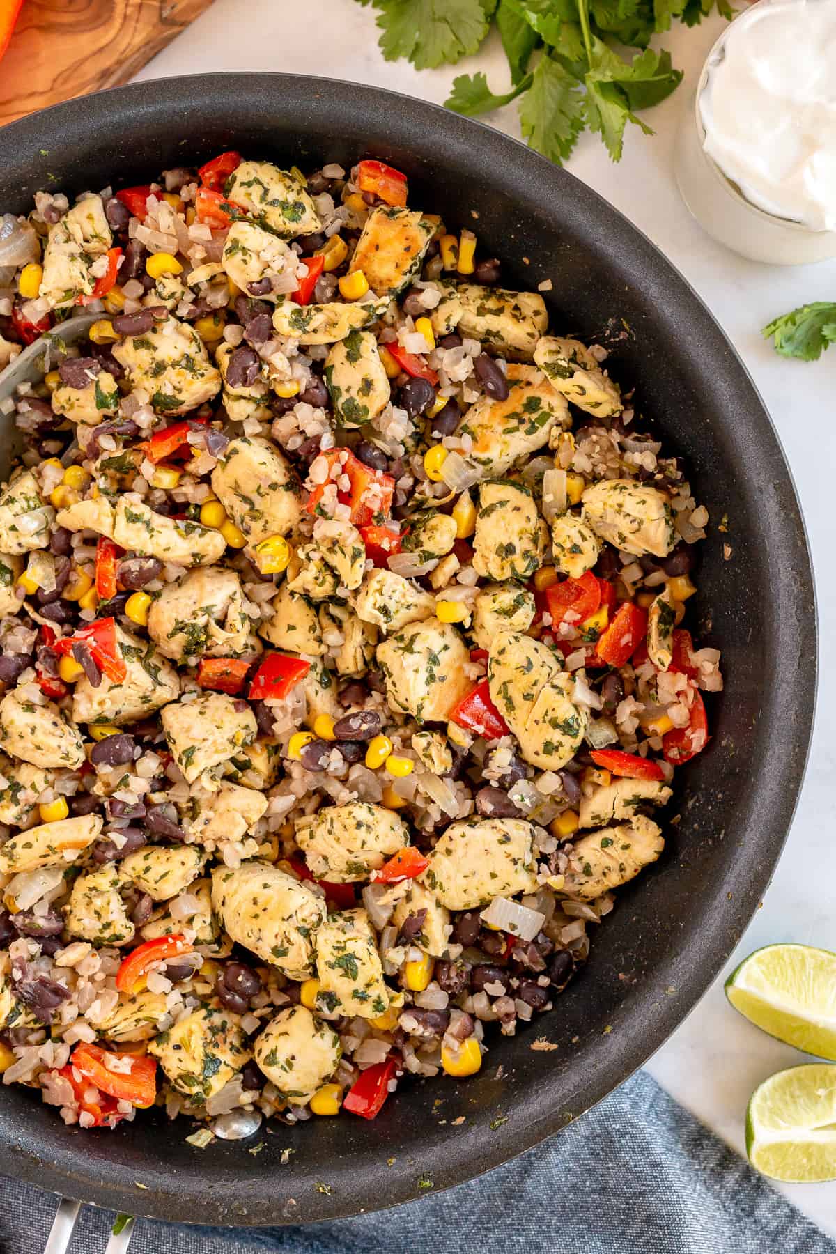 An over the top shot of a skillet filled with Cilantro Lime Chicken with Tex-Mex Cauliflower Rice.