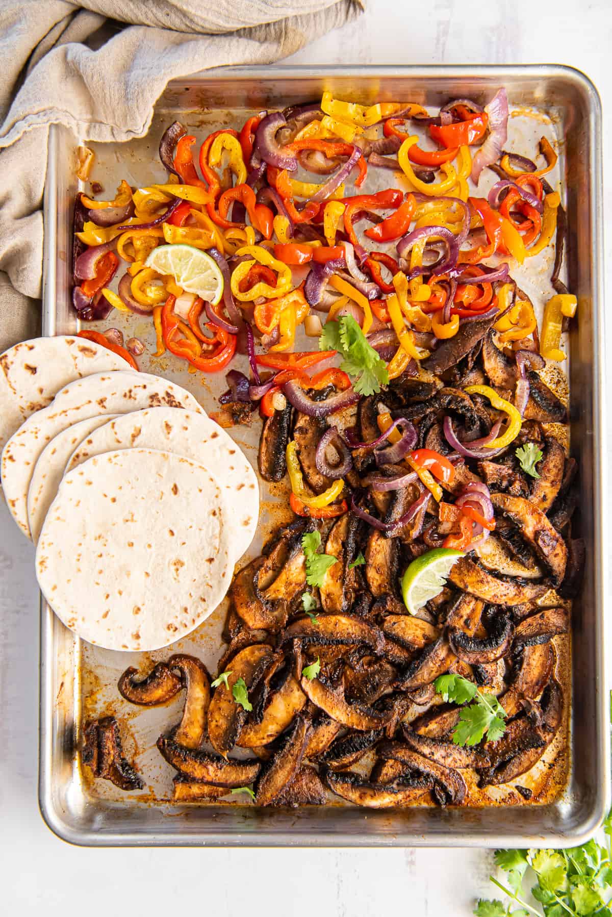 Roasted portobello mushrooms, peppers and onions and a baking sheet with small flour tortillas.