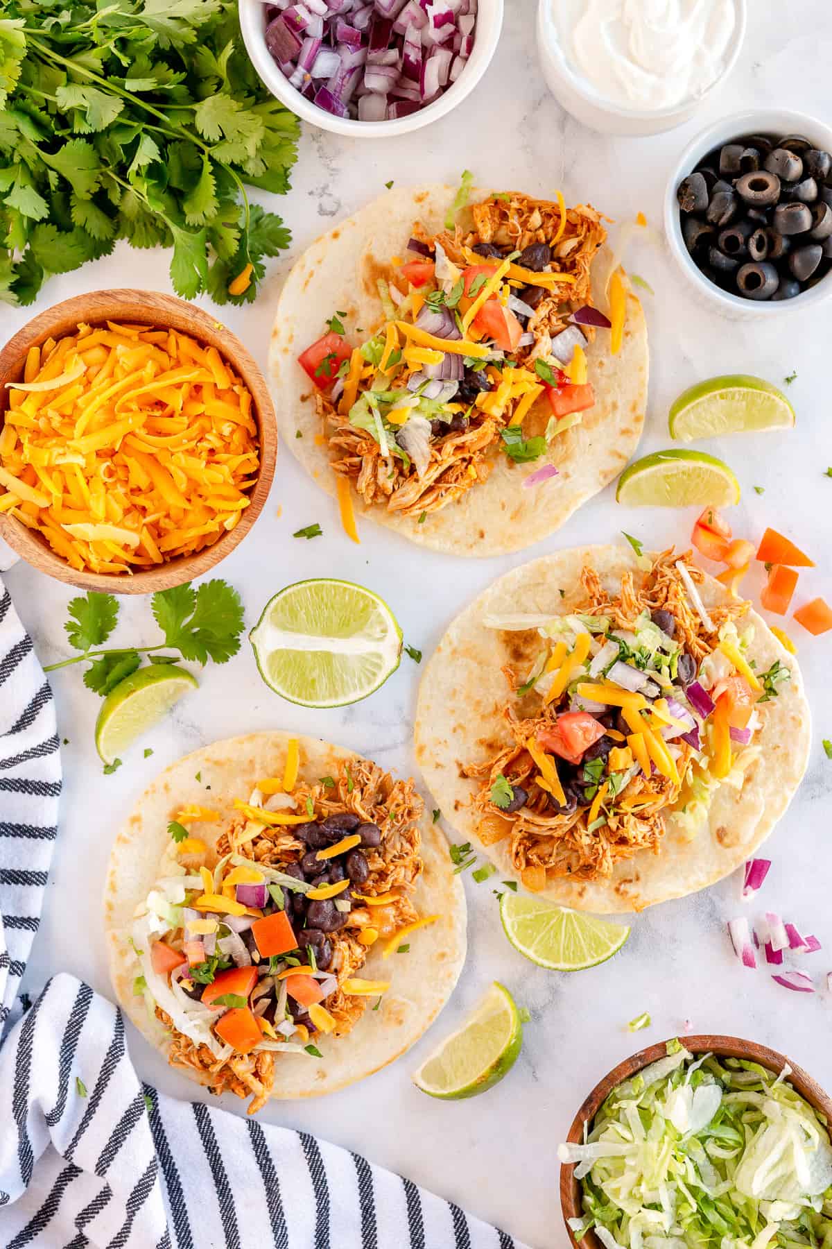 Rotisserie chicken and taco toppings on top of three flour tortillas.