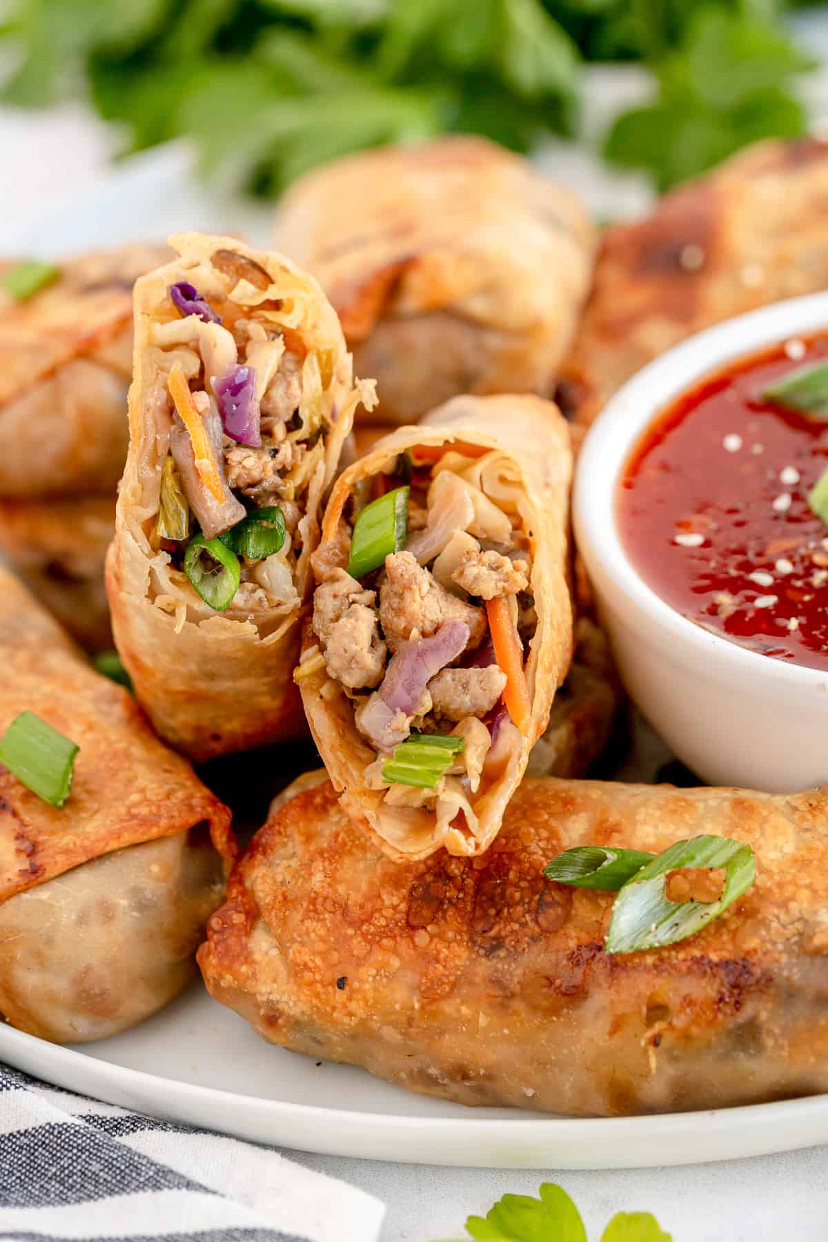 A platter of egg rolls with a small bowl of sweet chili sauce.