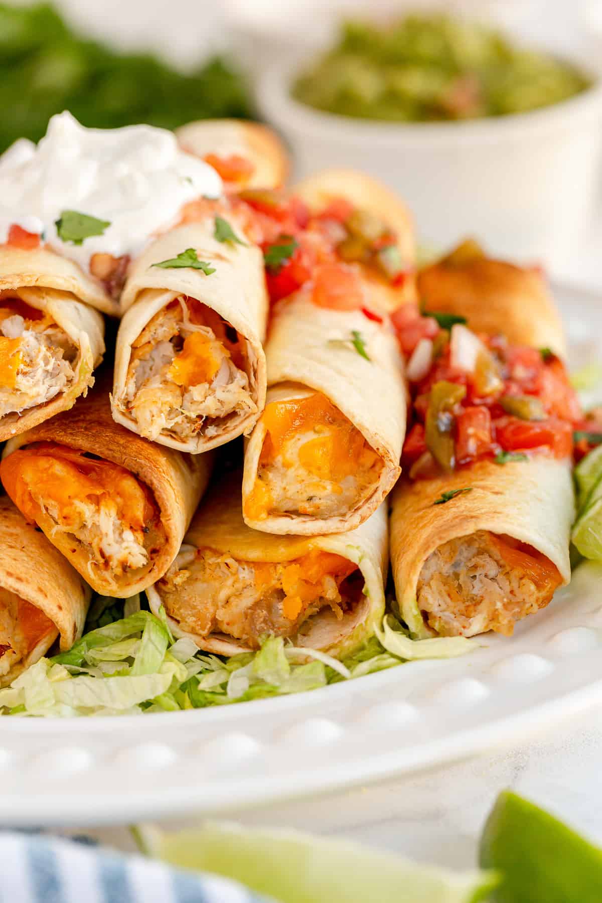 An eye level view of chicken taquitos on a plate.