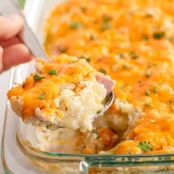 A spoon lifts a scoop of Cauliflower Ham Casserole from a baking dish.