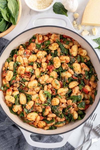 An over the top shot of a skillet of gnocchi with white beans.