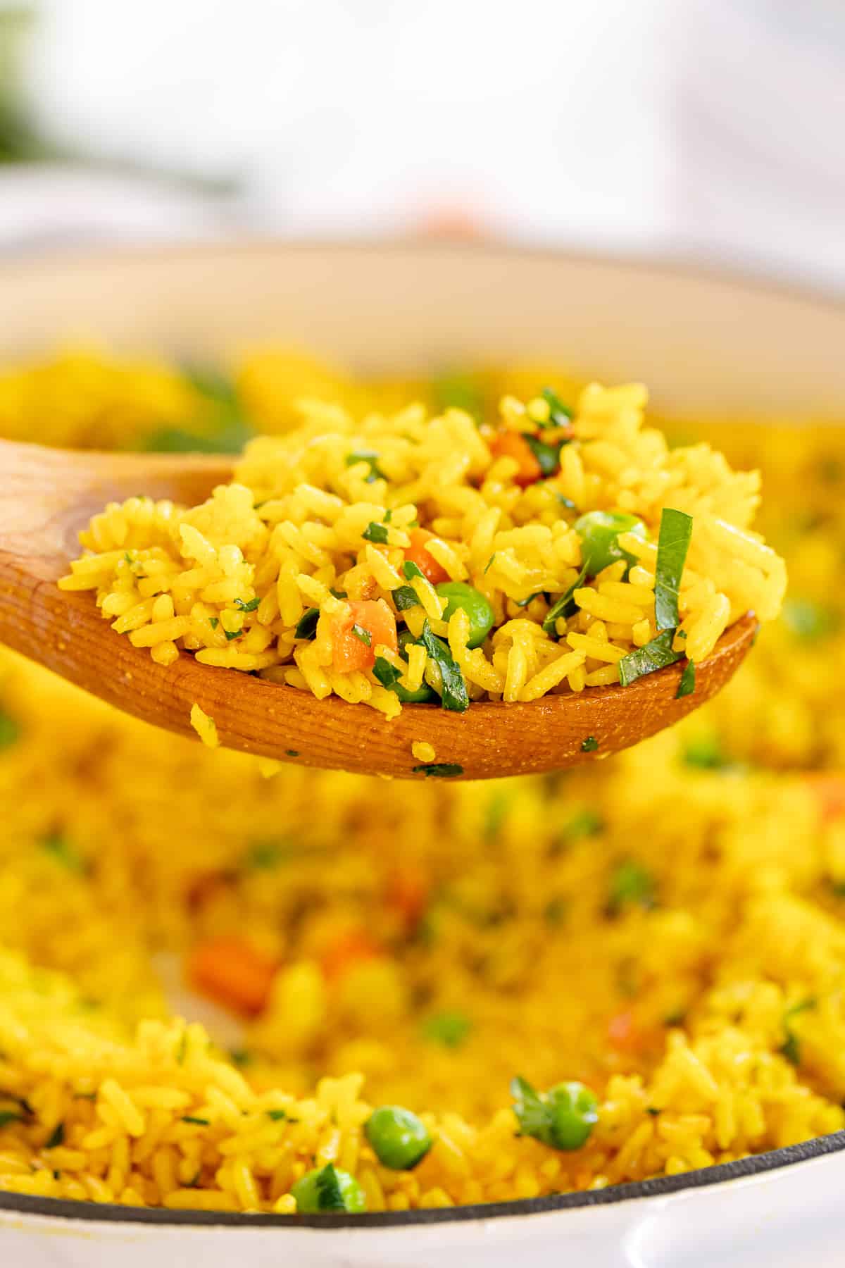 A wooden spoon holding a scoop of Yellow Rice.
