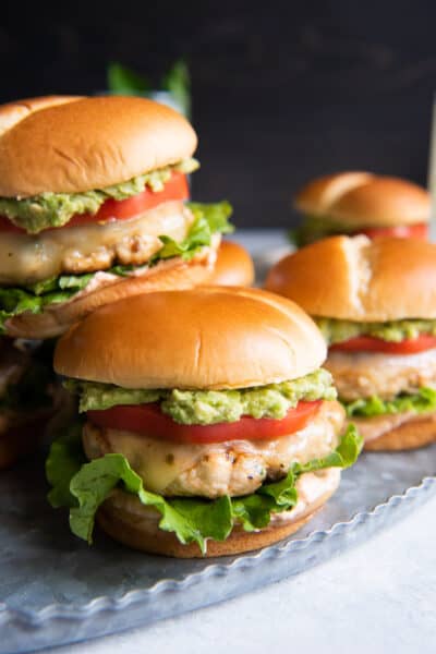 Ground chicken burgers stacked on a metal tray.