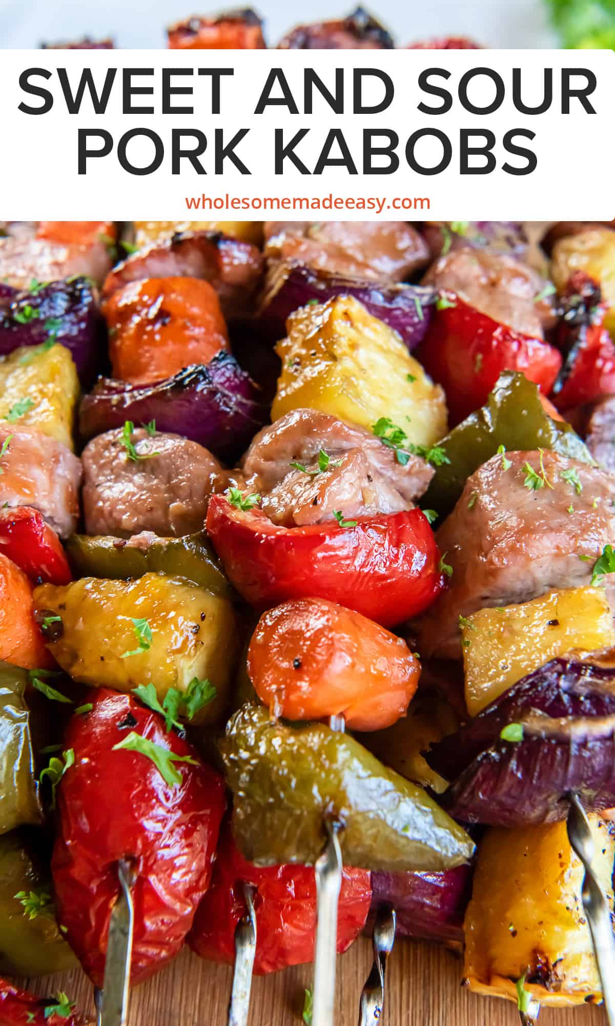 A closeup of pork kabobs with pineapple, peppers, and onions with text.