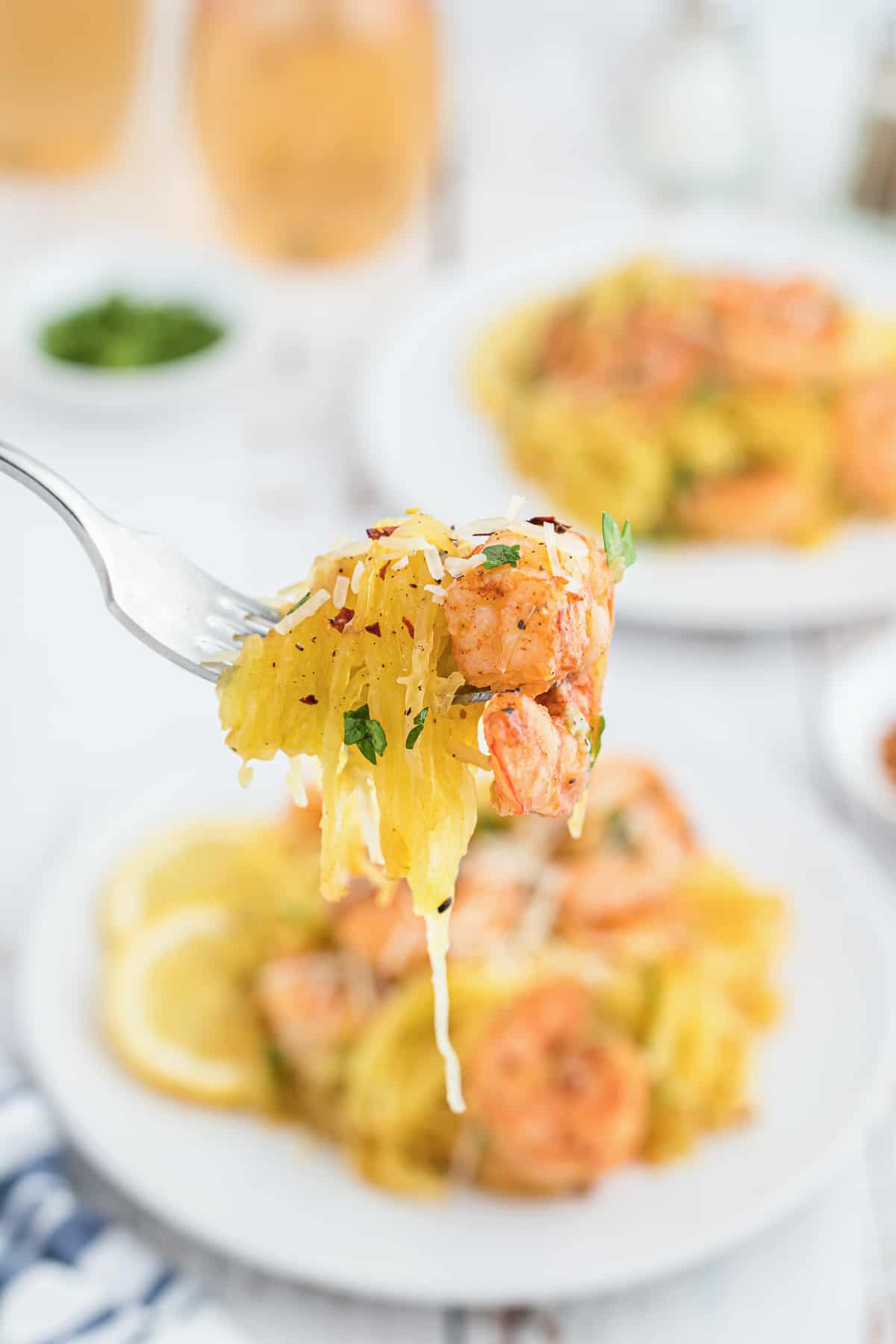 A fork lifts a bite of shrimp with spaghetti squash.