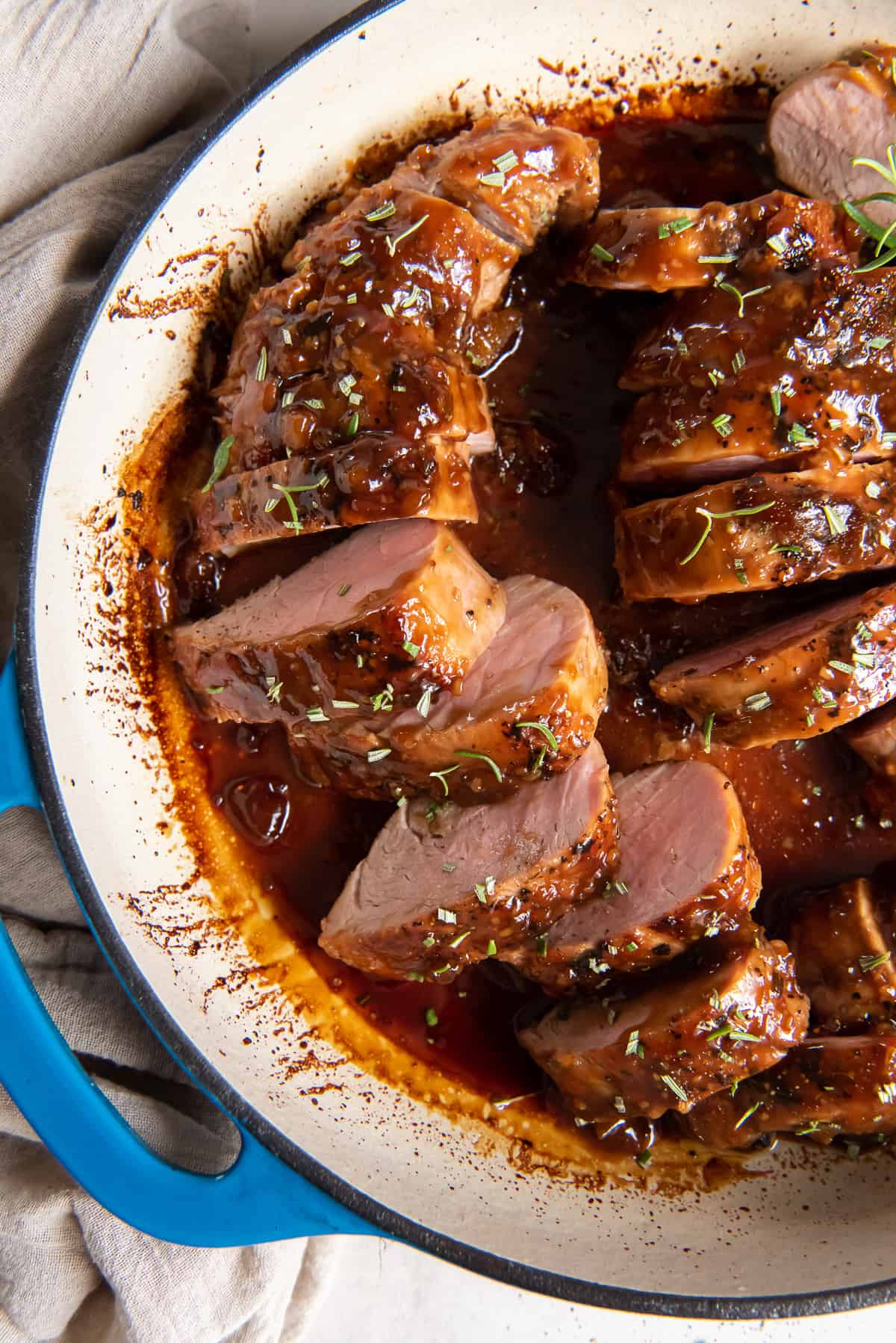 A top down shot of slices of Apricot Glazed Pork Tenderloin in a pan with sauce.