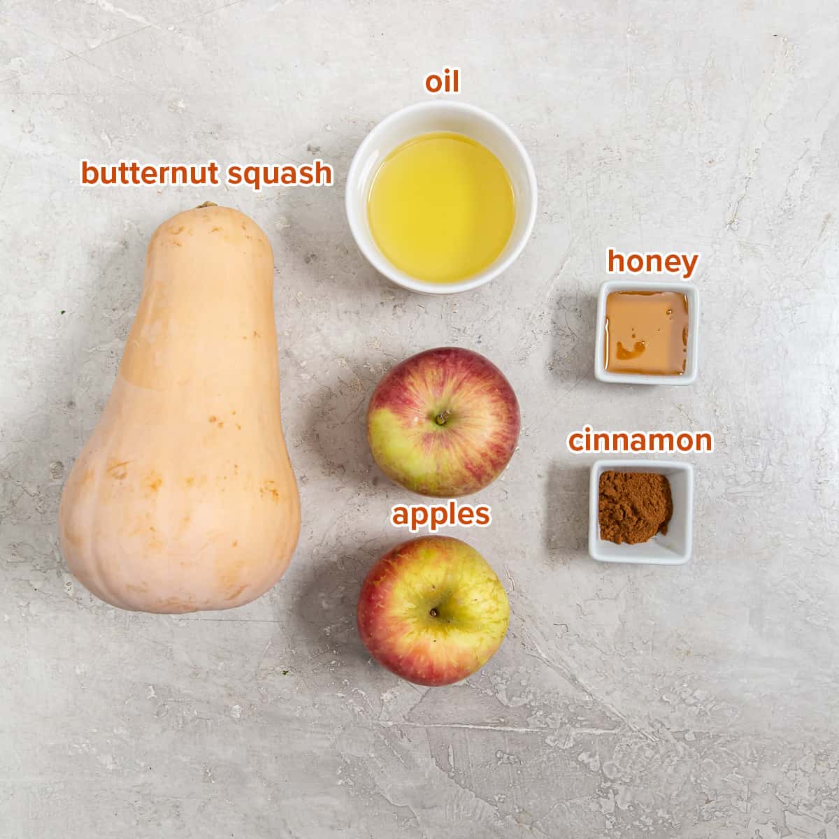 A butternut squash, two apples and oil, cinnamon, and honey in small bowls with text.