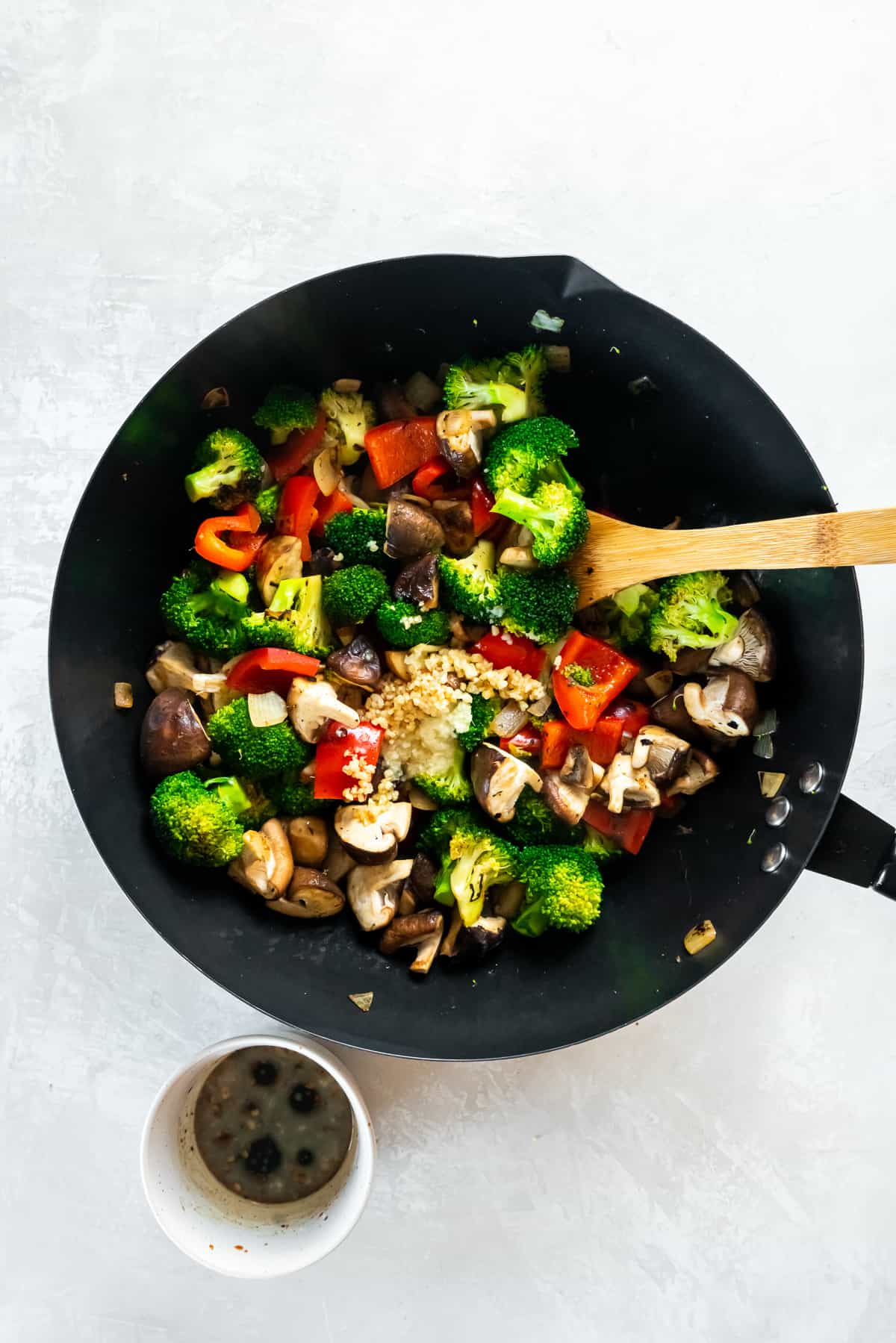 Broccoli mushroom stir fry in a wok with a wooden spoon.