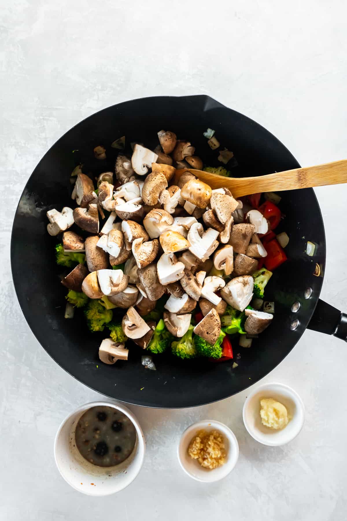 Mushrooms in a wok on top of other vegetables.