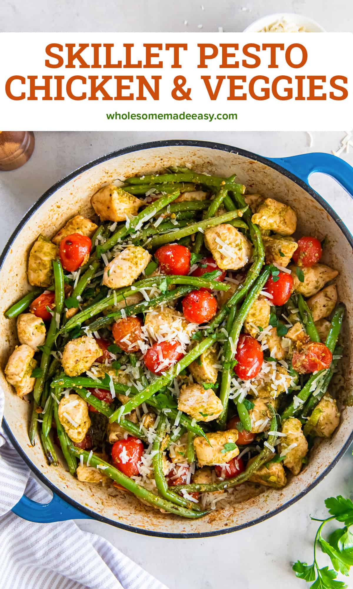 A top down shot of chicken with pesto and vegetables in a skillet with text.