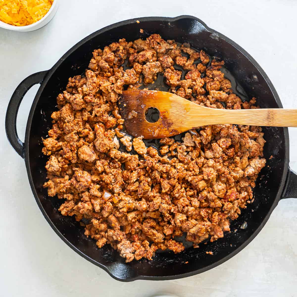 Cooked ground turkey taco filling in a cast iron skillet with a wooden spoon.