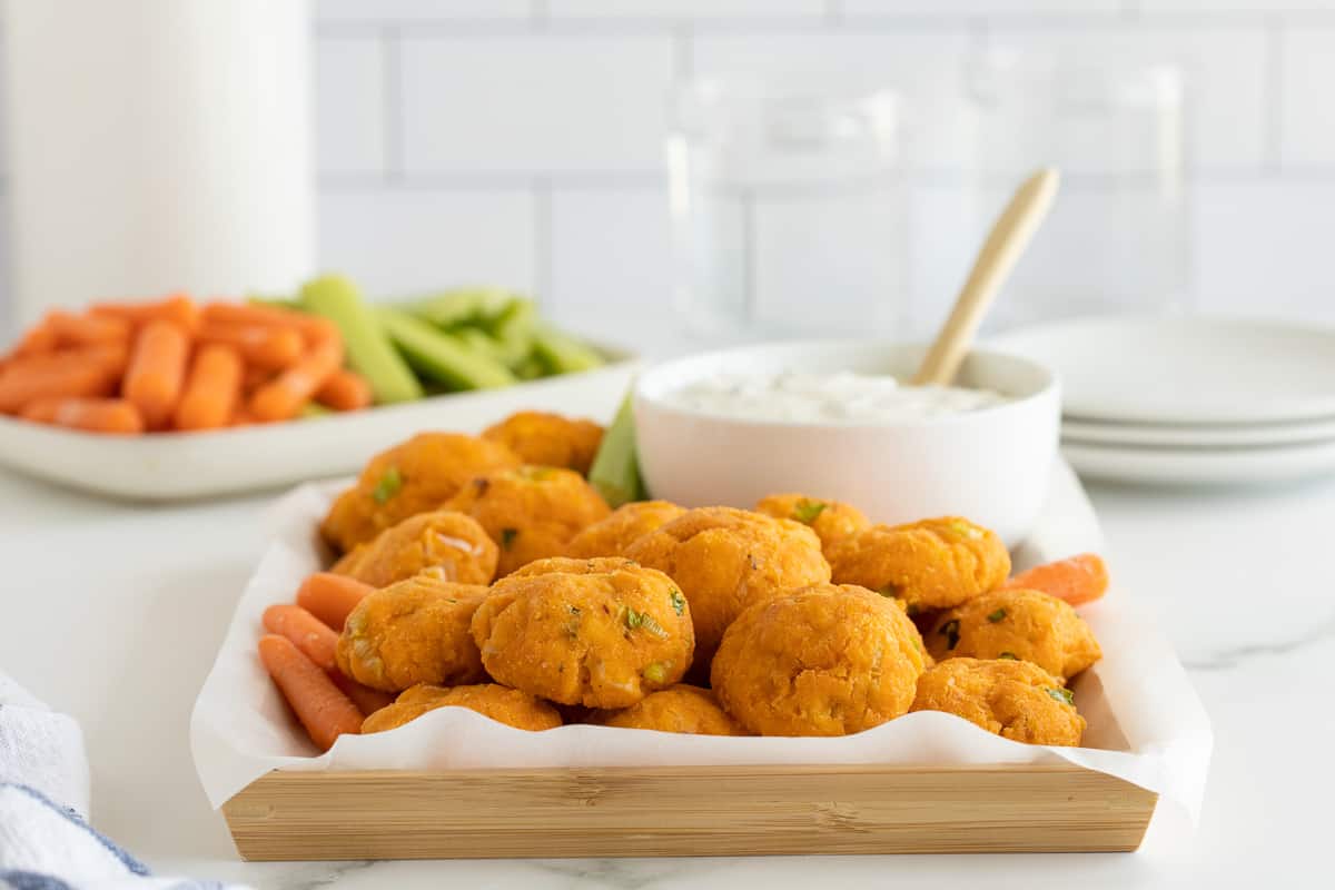 A side view of a platter of buffalo chicken bites on a kitchen counter.