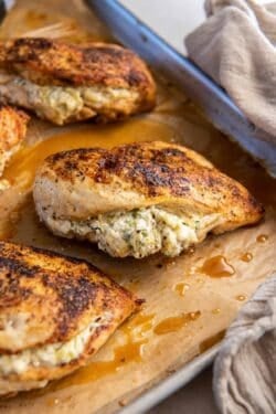 Stuffed chicken breasts on a baking sheet lined with parchment paper.