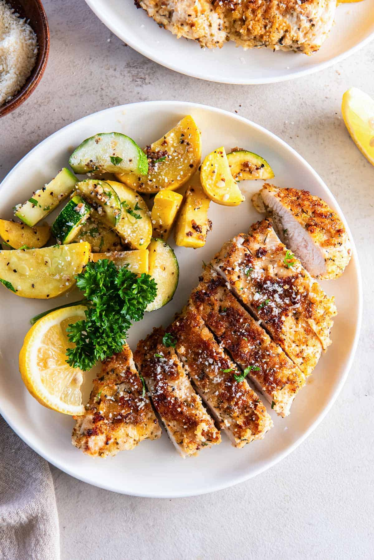 Breaded sliced chicken on a plate with green and yellow zucchini.