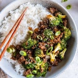 A bowl of white rice and Asian ground beef and broccoli with chopsticks.