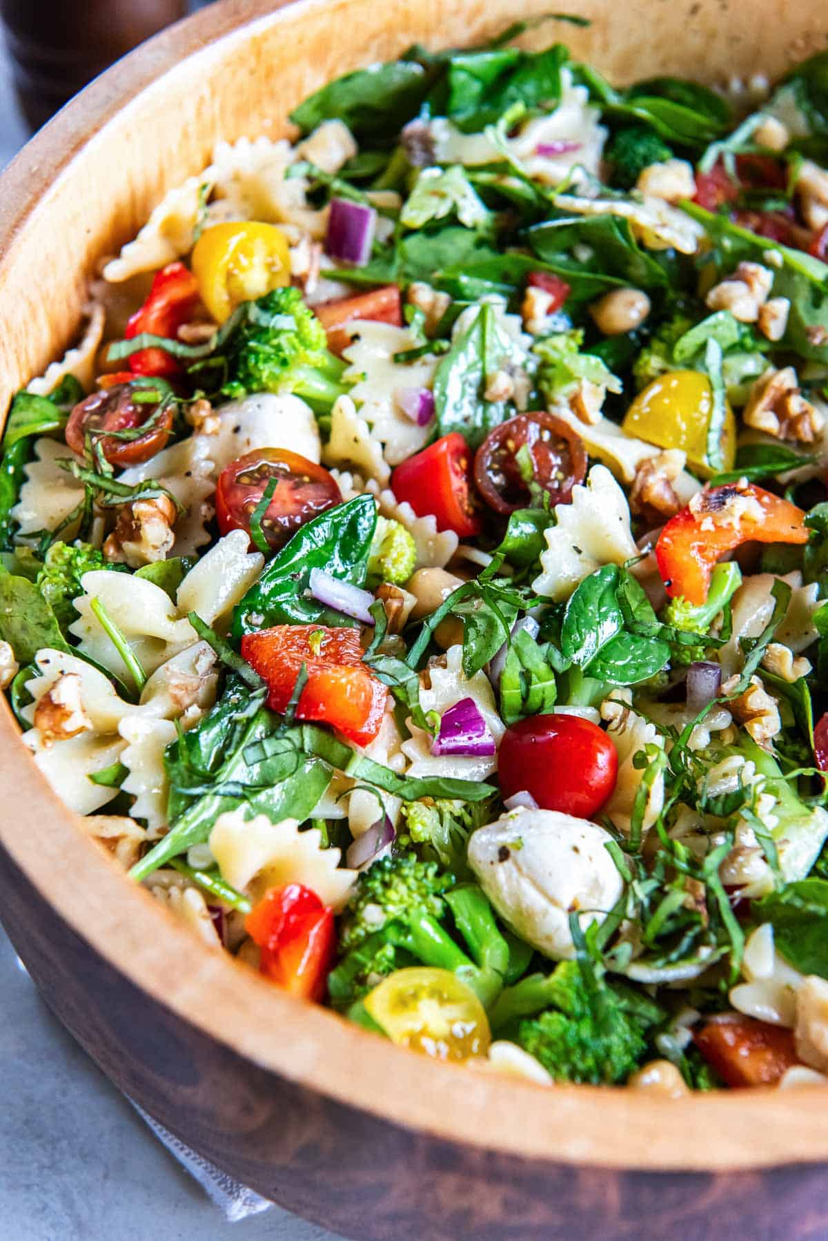Spinach pasta salad in a wood salad bowl.