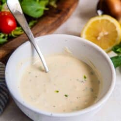 Greek yogurt salad dressing in a bowl with a spoon in front of a green salad.