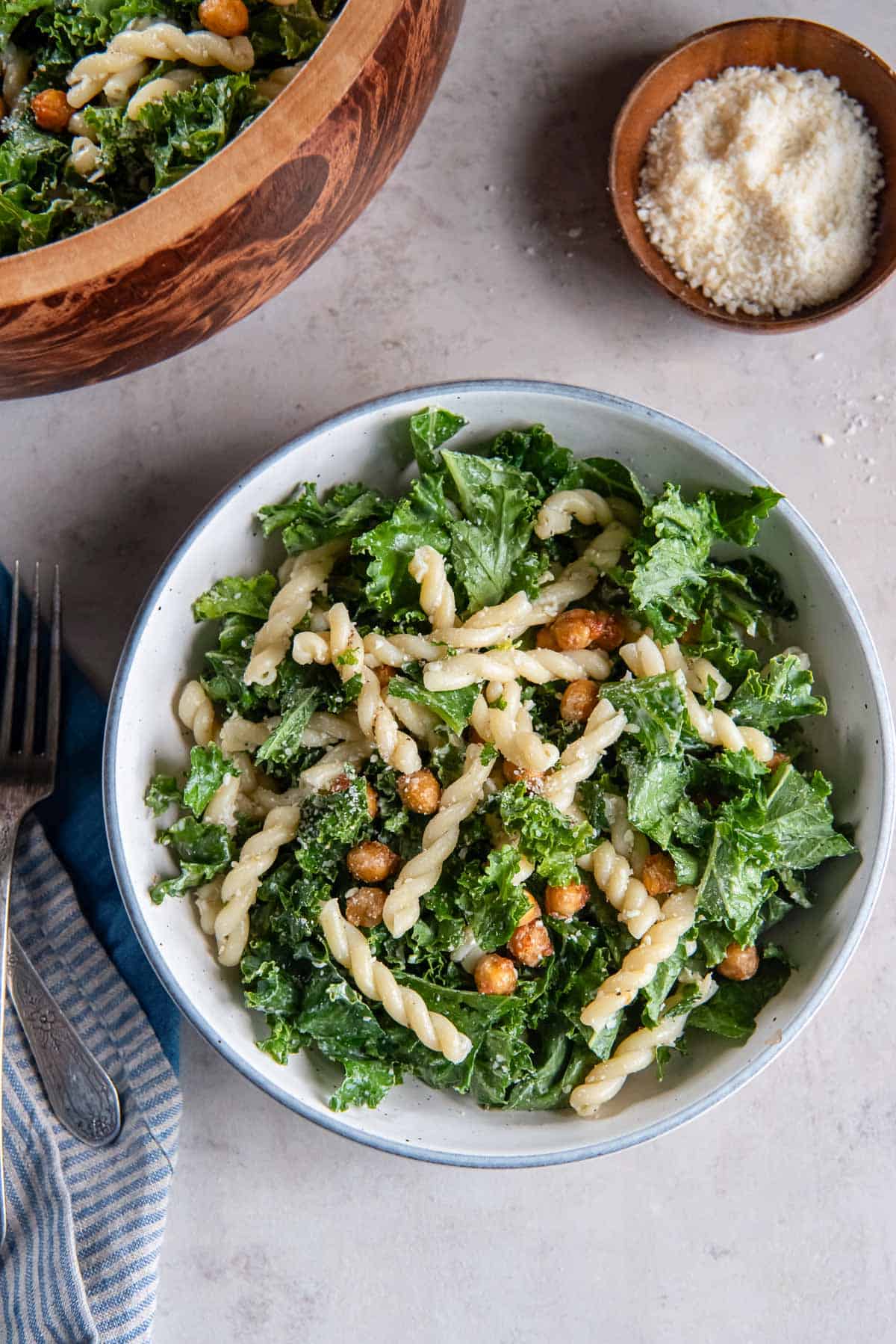 A serving of kale caesar pasta salad in a white bowl.