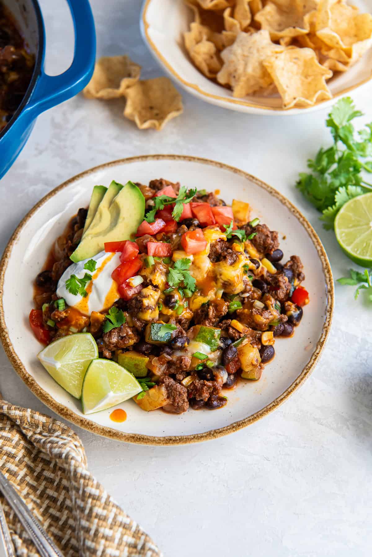 A serving of loaded taco skillet topped with sour cream and avocado on a white plate.