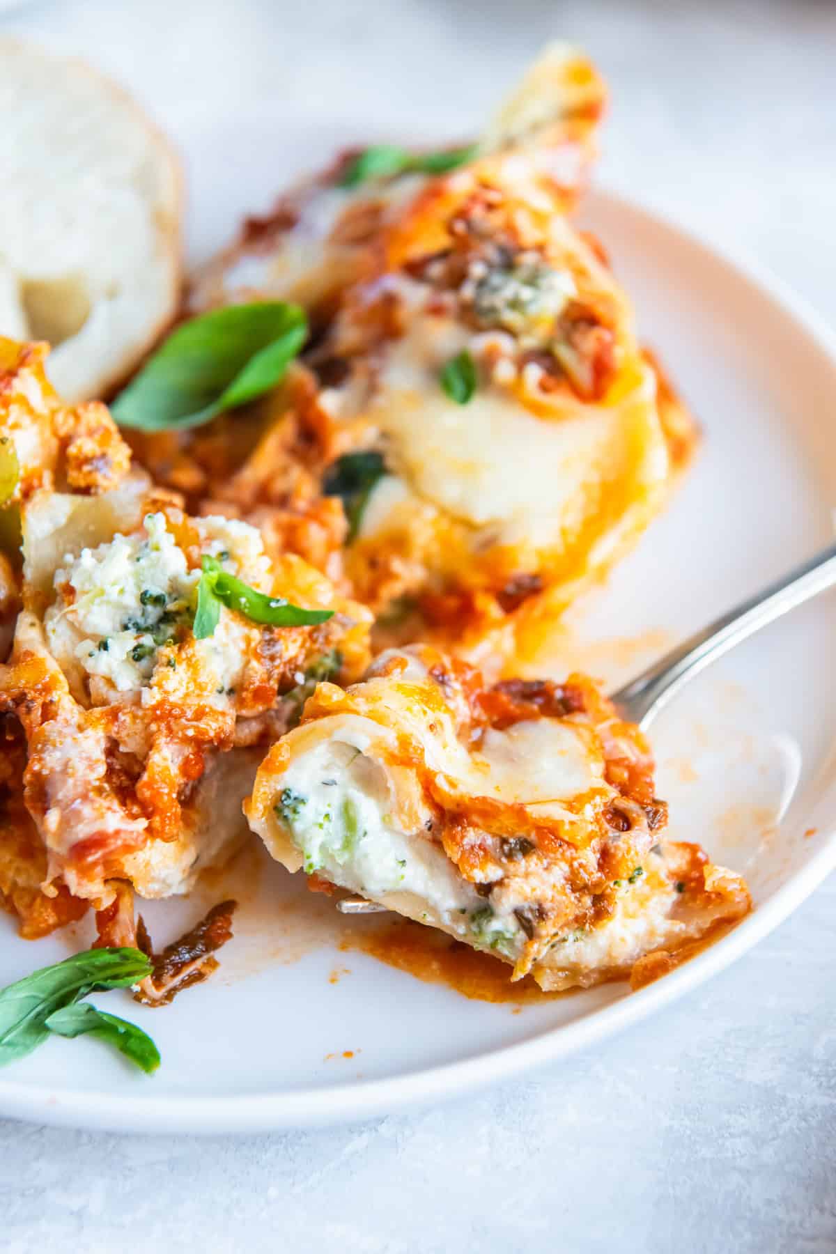 A fork resting on a plate with broccoli cheese stuffed shells.