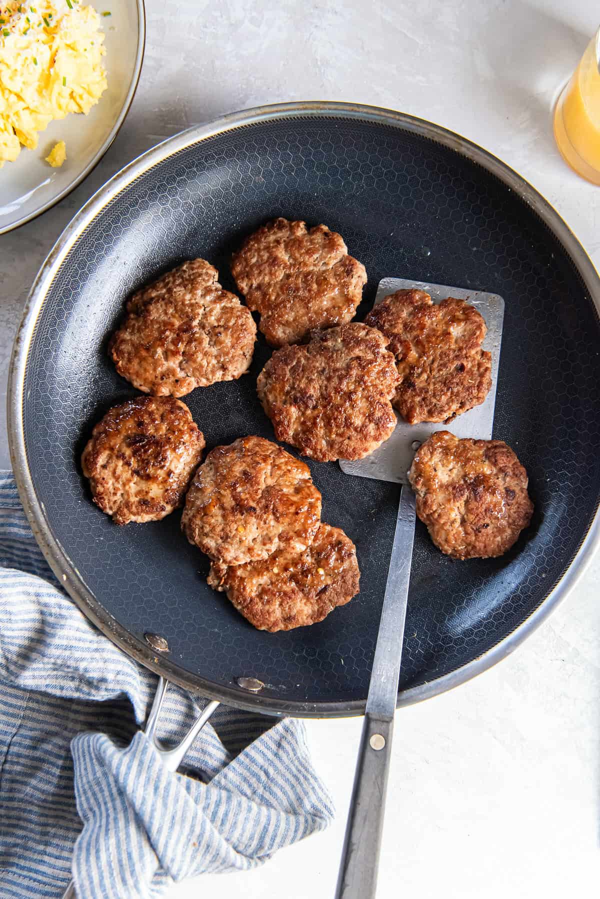 Turkey breakfast sausage patties in a skillet with a spatula.