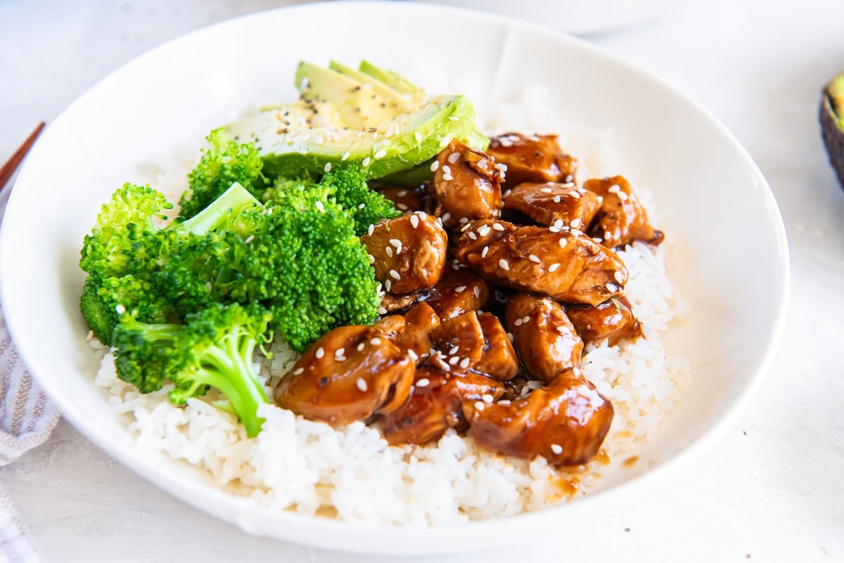 Chicken teriyaki, broccoli and avocado over white rice in a bowl.