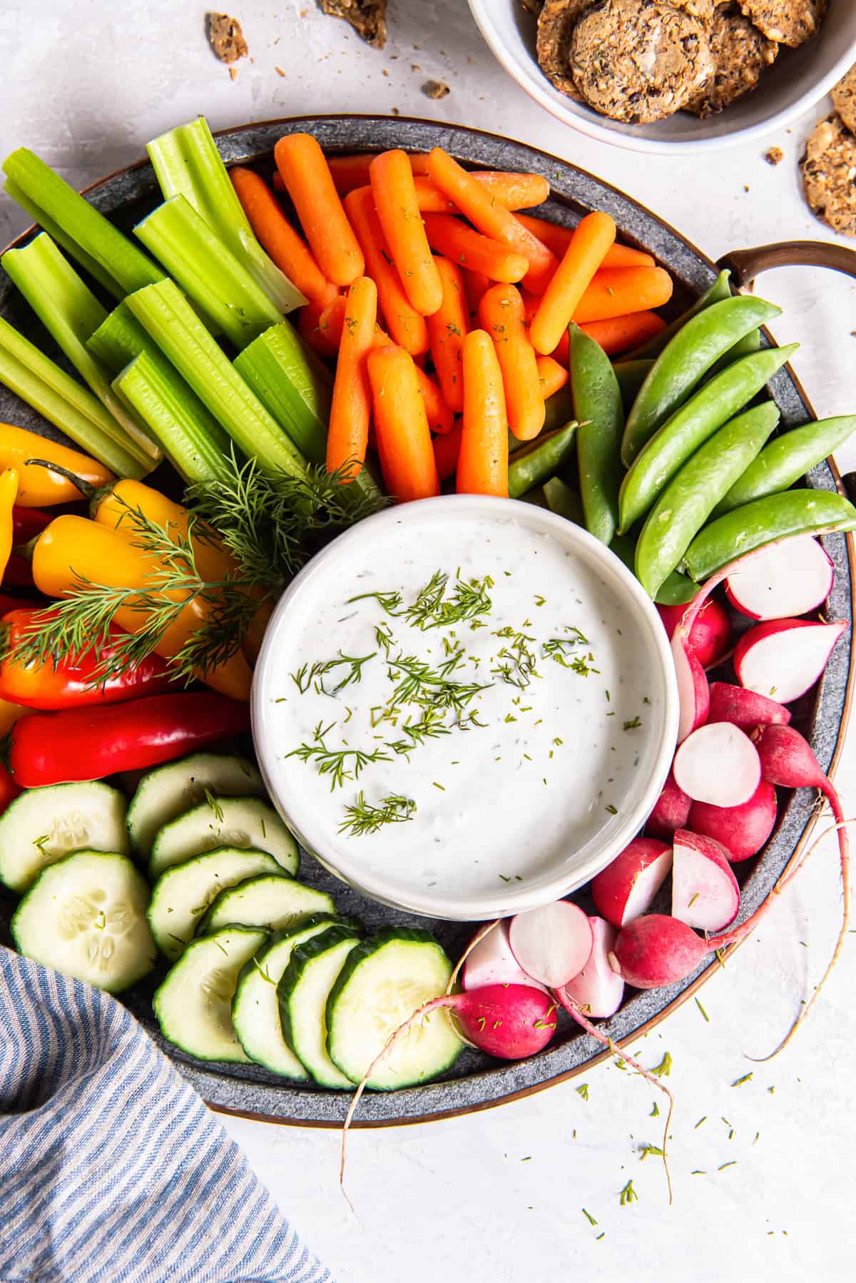 A platter of vegetables with a small bowl of cottage cheese dip garnished with fresh dill.